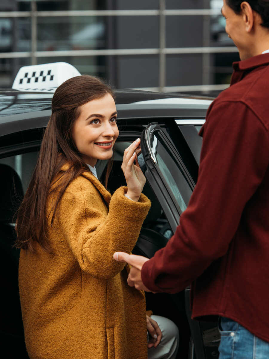 taxi driver opening auto door for smiling woman 2023 11 27 04 51 17 utc 1 1